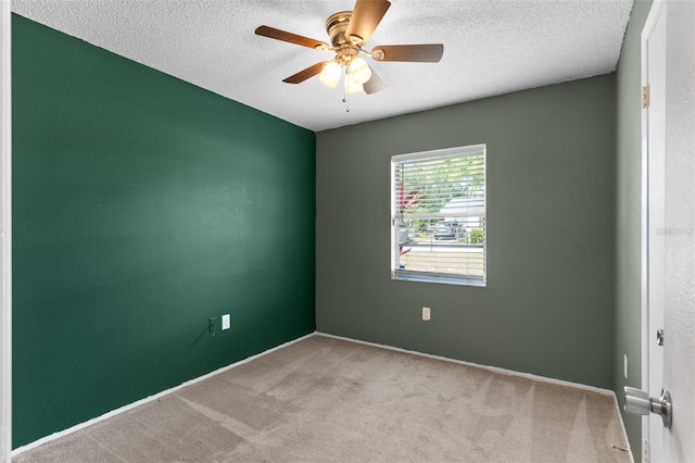 carpeted spare room featuring a textured ceiling and ceiling fan