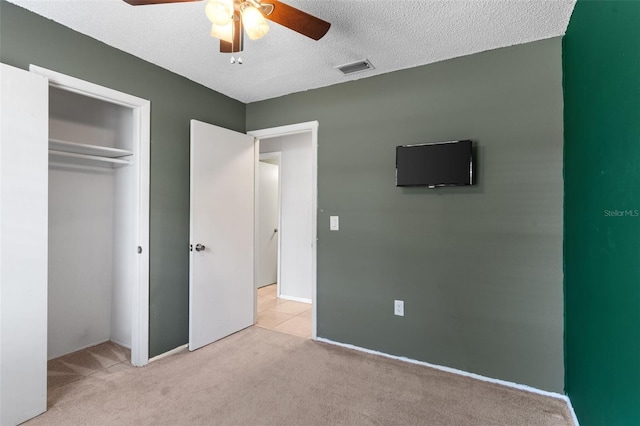 unfurnished bedroom featuring a ceiling fan, visible vents, a closet, a textured ceiling, and carpet flooring