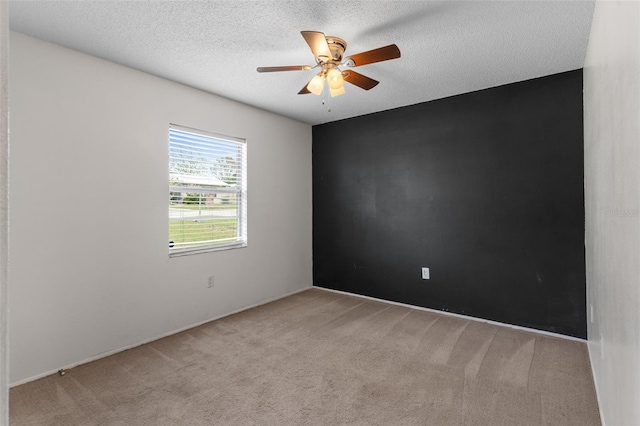 spare room with ceiling fan, light colored carpet, and a textured ceiling