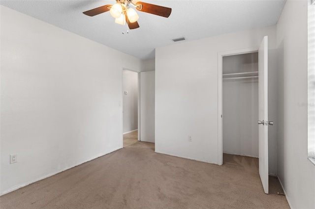 unfurnished bedroom featuring visible vents, carpet flooring, a closet, a textured ceiling, and a ceiling fan