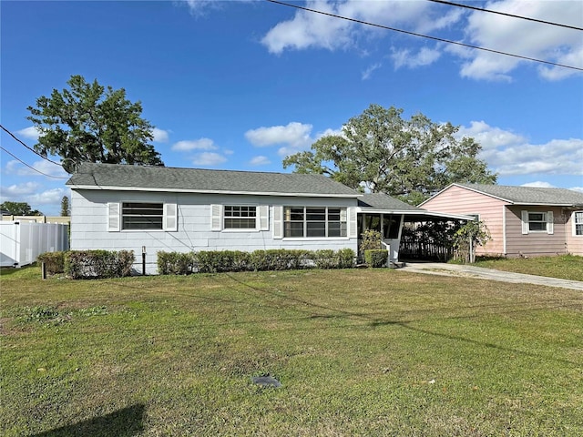 ranch-style home featuring a carport, concrete driveway, a front lawn, and fence