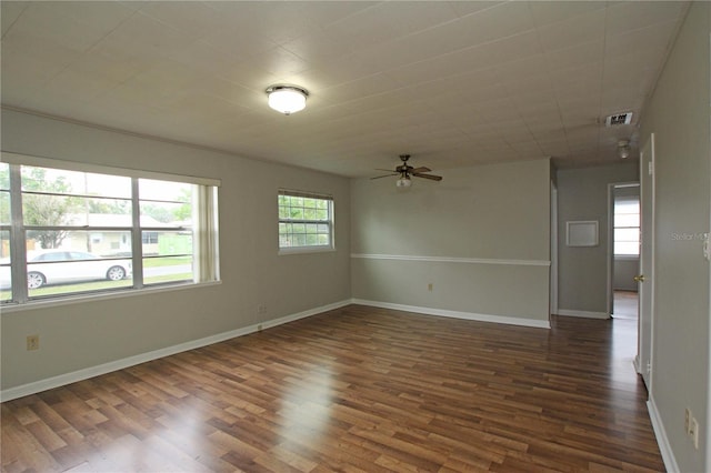 spare room with a ceiling fan, visible vents, dark wood-style floors, and baseboards