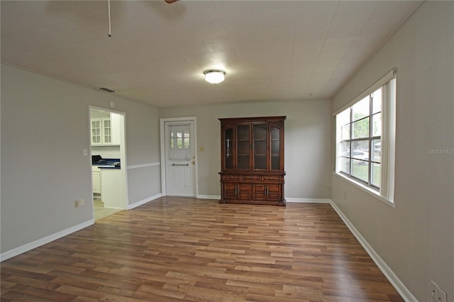 spare room featuring visible vents, baseboards, and wood finished floors