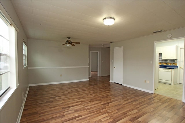 empty room with light wood finished floors, visible vents, and baseboards