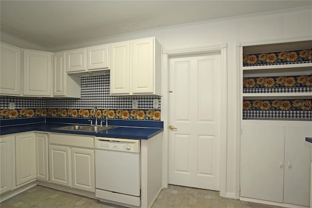 kitchen with dark countertops, a sink, ornamental molding, and white dishwasher