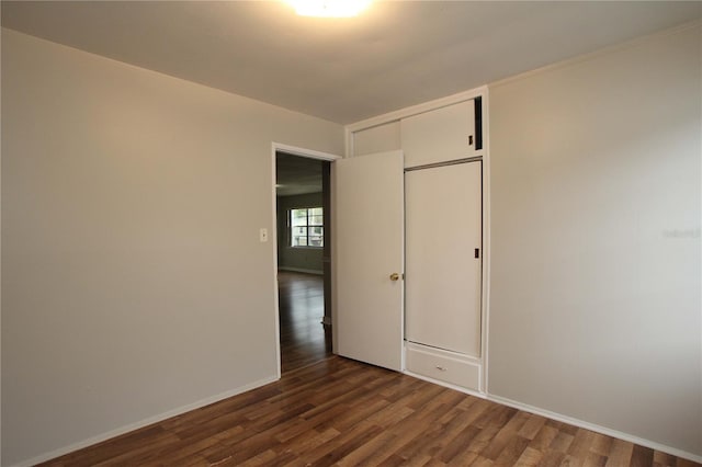 unfurnished room with baseboards and dark wood-style flooring