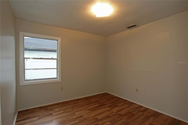 empty room featuring visible vents, baseboards, and wood finished floors