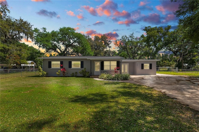 ranch-style home featuring driveway, a front lawn, and fence