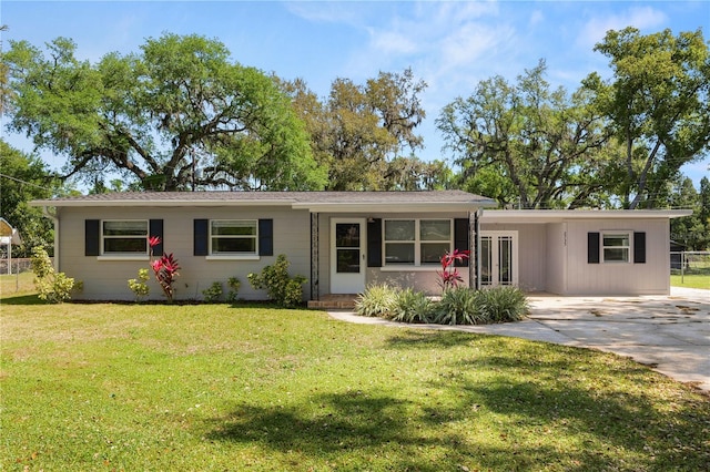 ranch-style home with an attached carport, fence, concrete driveway, a front yard, and french doors