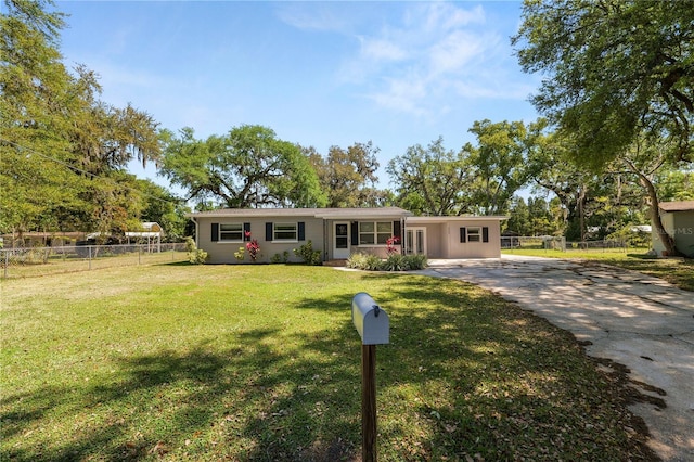 ranch-style home with a front yard, driveway, and fence