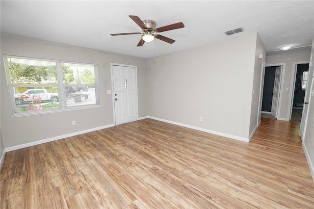 spare room featuring a ceiling fan, baseboards, visible vents, and light wood finished floors