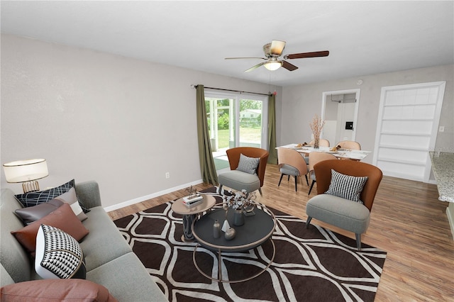 living area featuring wood finished floors, baseboards, and ceiling fan