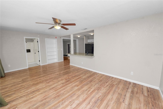 unfurnished living room featuring baseboards, a ceiling fan, and light wood finished floors