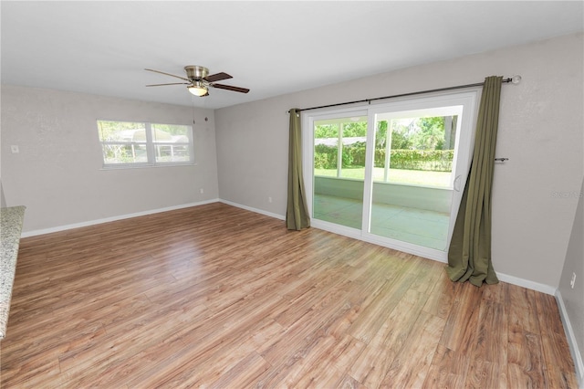 empty room featuring light wood finished floors, a ceiling fan, and a wealth of natural light