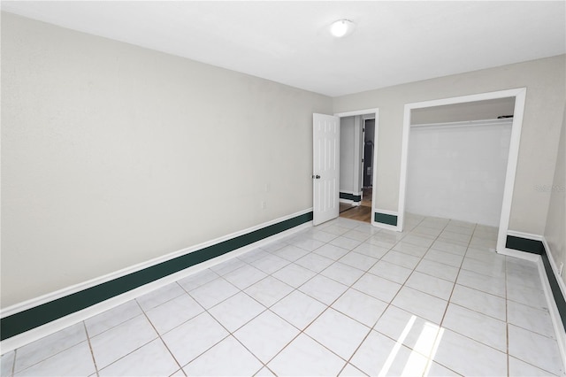 unfurnished bedroom featuring light tile patterned floors, a closet, and baseboards