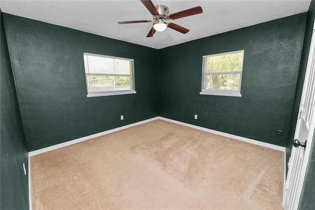 carpeted empty room with a ceiling fan, a textured wall, and baseboards