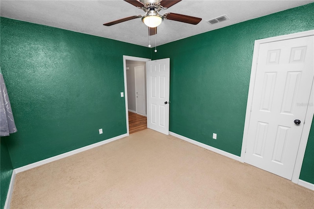 unfurnished bedroom featuring baseboards, visible vents, ceiling fan, carpet flooring, and a textured wall