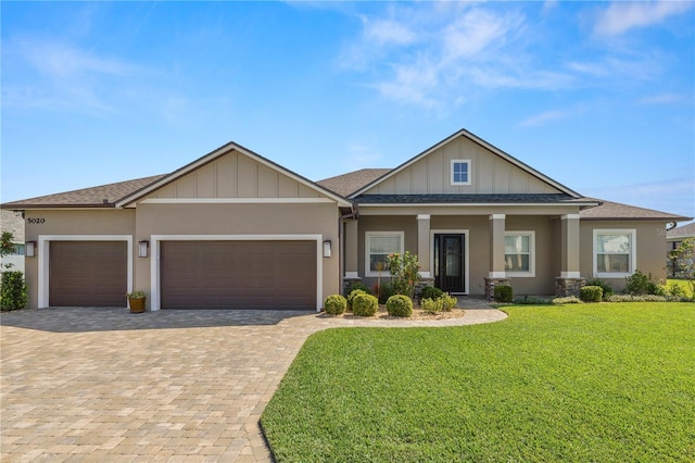 craftsman inspired home featuring stucco siding, a front lawn, decorative driveway, a shingled roof, and a garage