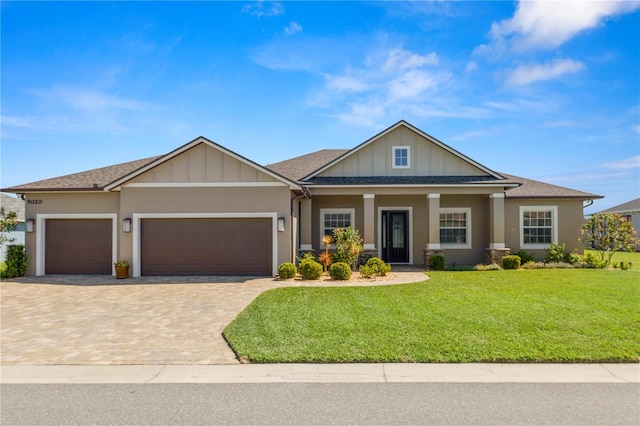 view of front of home with an attached garage, a shingled roof, a front lawn, decorative driveway, and board and batten siding