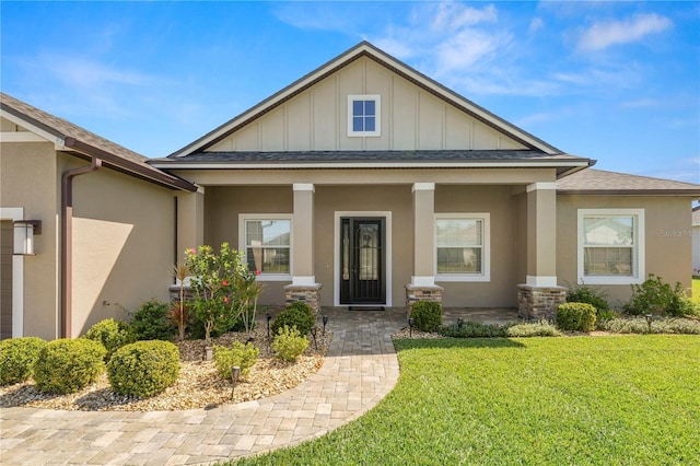 view of front of property featuring stucco siding, roof with shingles, a porch, and a front yard