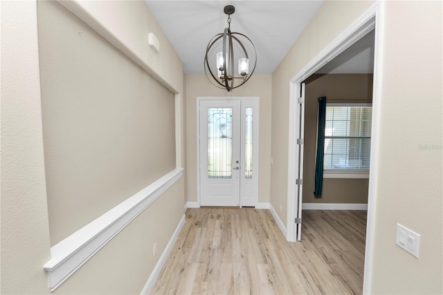 entrance foyer featuring an inviting chandelier, baseboards, and light wood finished floors