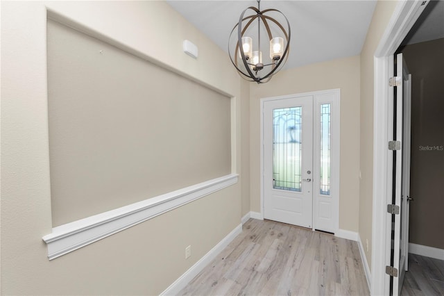 entrance foyer featuring baseboards, an inviting chandelier, and wood finished floors