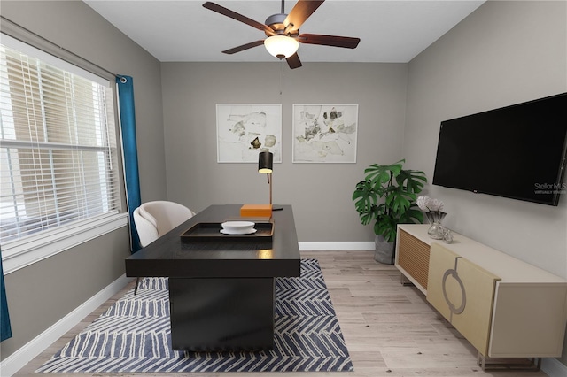 office space with baseboards, light wood-style floors, and a ceiling fan