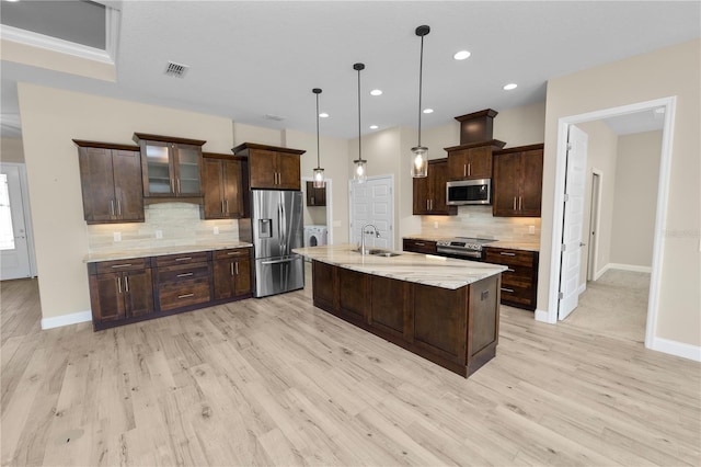 kitchen with visible vents, light wood-style flooring, a sink, stainless steel appliances, and dark brown cabinetry