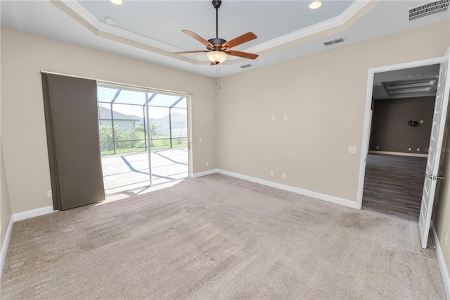 empty room featuring visible vents, a ceiling fan, a raised ceiling, and carpet