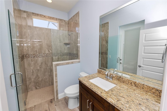 full bathroom featuring toilet, wood finished floors, vanity, and a tile shower