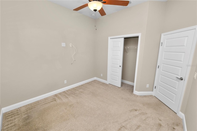 unfurnished bedroom featuring a closet, light colored carpet, a ceiling fan, and baseboards