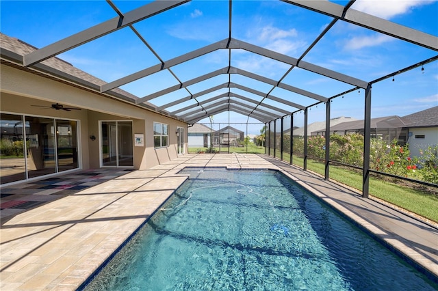 pool with a patio area, glass enclosure, and a ceiling fan