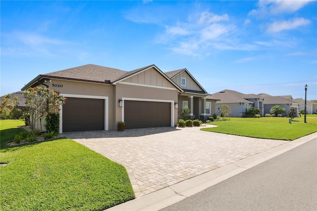 view of front facade featuring an attached garage, stucco siding, a shingled roof, a front lawn, and decorative driveway