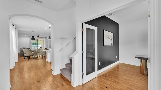 staircase featuring visible vents, baseboards, hardwood / wood-style floors, recessed lighting, and arched walkways