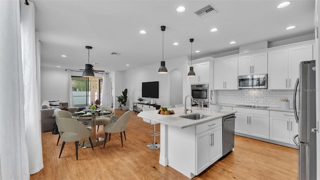 kitchen with visible vents, open floor plan, decorative backsplash, stainless steel appliances, and a sink