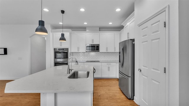 kitchen with decorative backsplash, light wood-style flooring, stainless steel appliances, and a sink