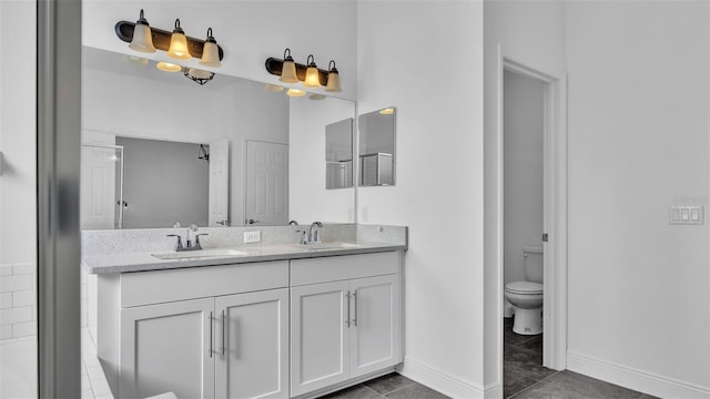 full bath featuring double vanity, toilet, baseboards, and a sink