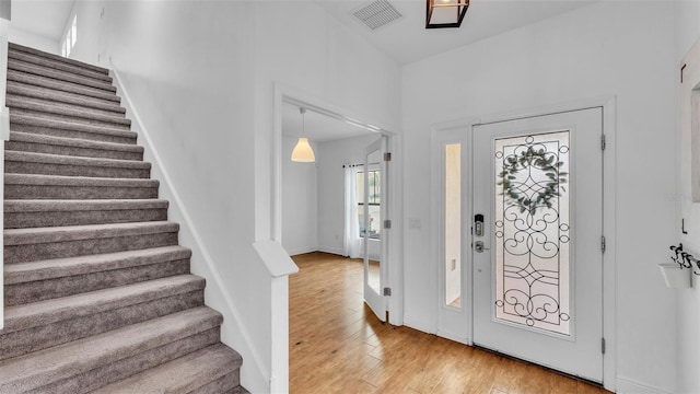 entrance foyer with visible vents, baseboards, light wood-style flooring, and stairway