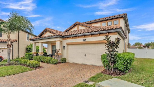 mediterranean / spanish-style home featuring fence, a tiled roof, stucco siding, a garage, and driveway