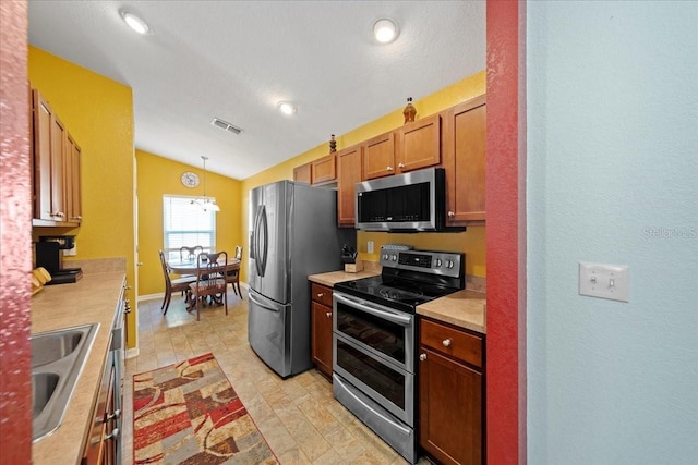 kitchen with visible vents, a sink, stainless steel appliances, light countertops, and vaulted ceiling