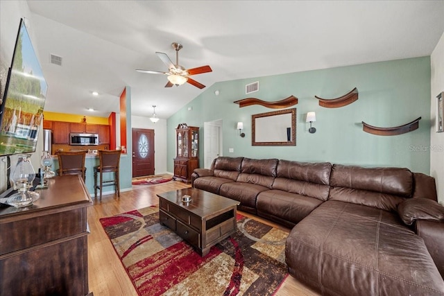 living room with visible vents, light wood-style floors, and vaulted ceiling