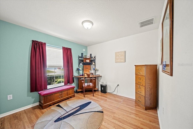 misc room with visible vents, baseboards, a textured ceiling, and wood finished floors