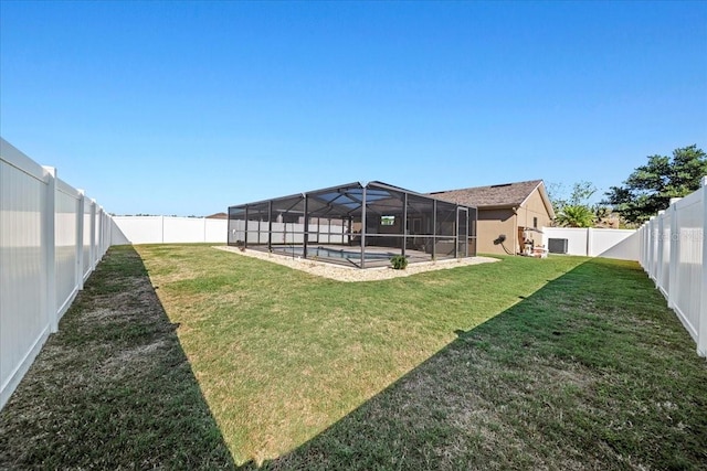 view of yard featuring glass enclosure, a fenced in pool, and a fenced backyard