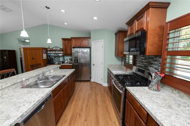 kitchen featuring visible vents, light wood-style flooring, a sink, stainless steel appliances, and vaulted ceiling