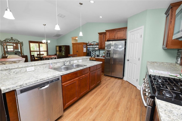 kitchen featuring pendant lighting, vaulted ceiling, light wood-style floors, stainless steel appliances, and a sink