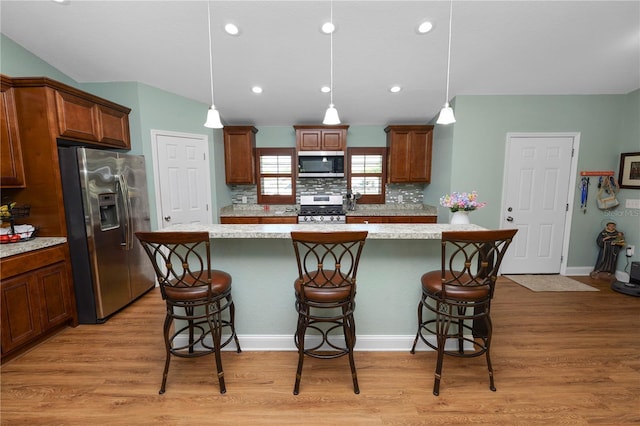 kitchen featuring decorative backsplash, stainless steel appliances, light countertops, and light wood-style floors