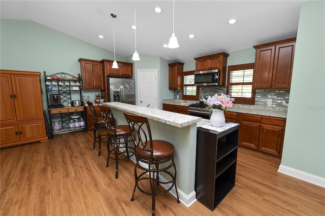 kitchen featuring light wood-style floors, appliances with stainless steel finishes, a breakfast bar area, and light countertops