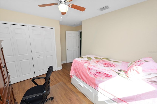 bedroom featuring baseboards, visible vents, light wood-style flooring, ceiling fan, and a closet