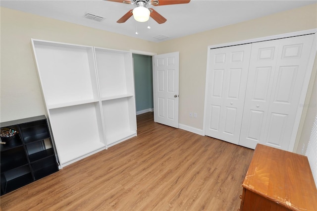 unfurnished bedroom with baseboards, visible vents, light wood finished floors, ceiling fan, and a closet