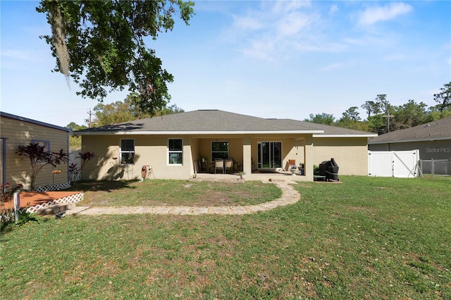 back of property with stucco siding, a gate, a patio, fence, and a yard